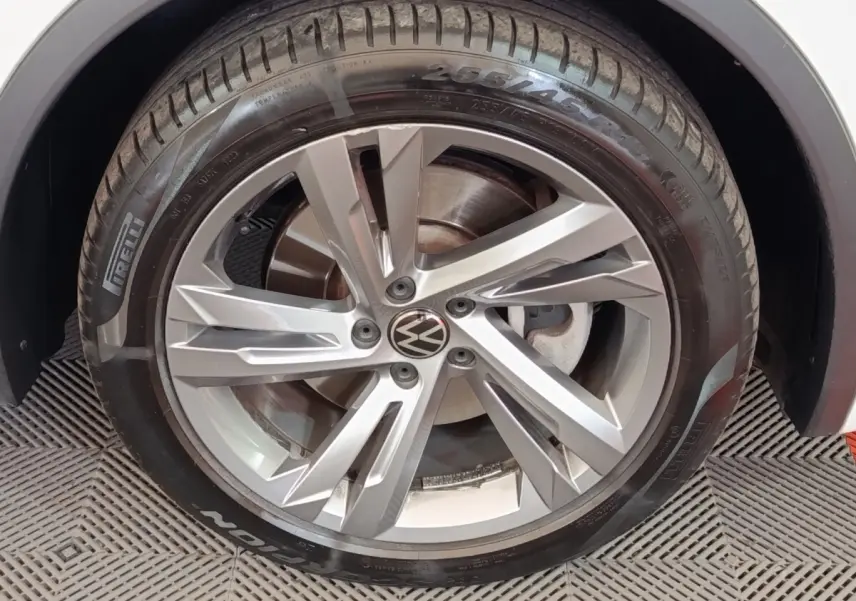 Gros plan sur la roue avant gauche avec jante alliage argentée et pneu Pirelli sur Volkswagen Tiguan blanc.