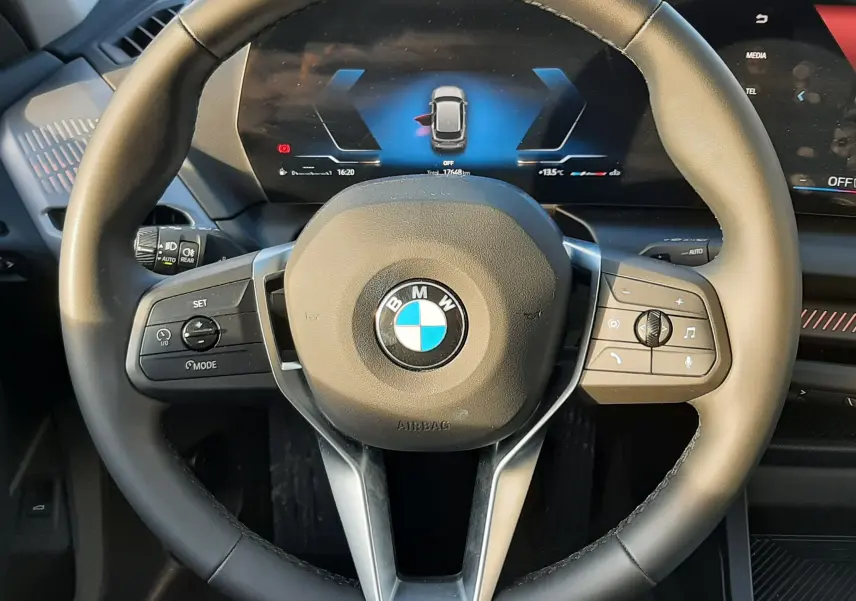 Vue rapprochée du volant noir de la BMW Série 1 120D 2025 avec tableau de bord numérique allumé.