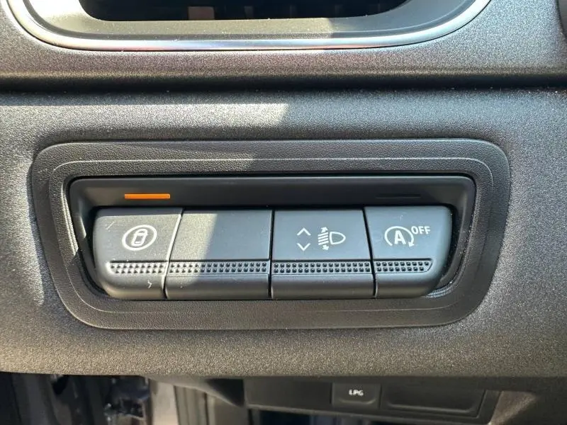 Gros plan sur les commandes noires du tableau de bord du Renault Captur 2025, avec bouton de verrouillage et réglage des phares.