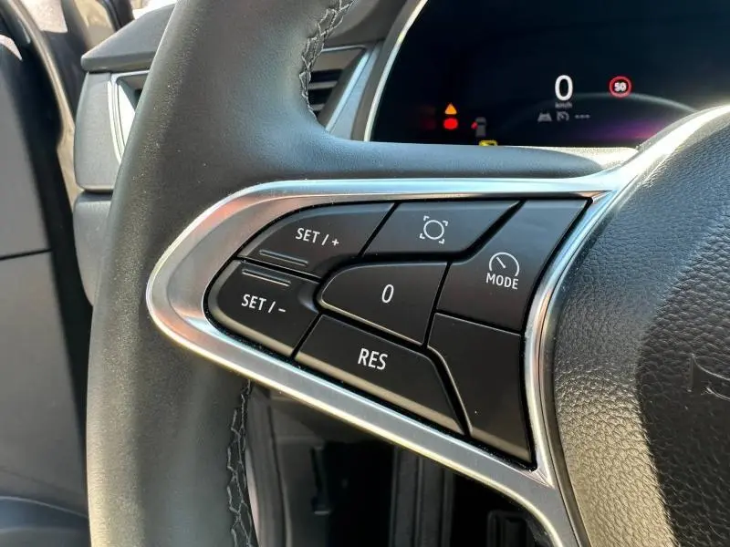Gros plan sur les commandes au volant à gauche du Renault Captur 2025, cuir noir et inserts argentés visibles.