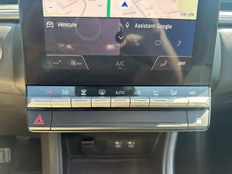 Gros plan sur la console centrale tactile du Renault Captur 2025 avec commandes climatisation et écran GPS visible.