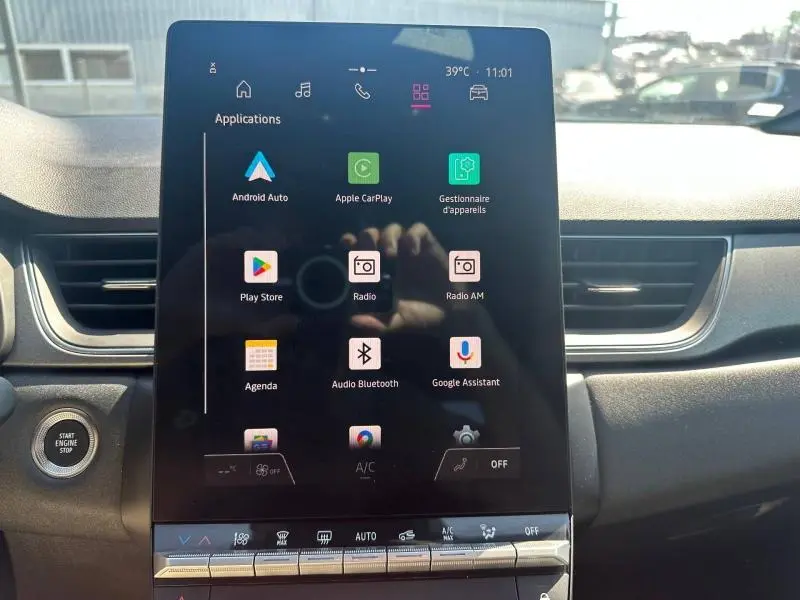 Écran tactile central allumé en intérieur de Renault Captur gris, vue frontale du tableau de bord avec commandes digitales.