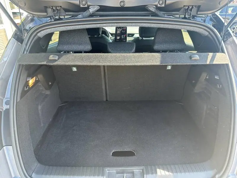 Coffre ouvert vu de l'arrière du Renault Captur gris Cassiopée métallisé avec tablette cache-bagages et sièges arrière visibles.
