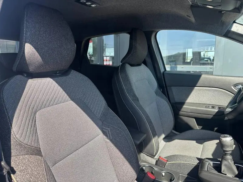 Vue intérieure côté avant droit du Renault Captur 2025, sièges tissu gris avec surpiqûres contrastantes.