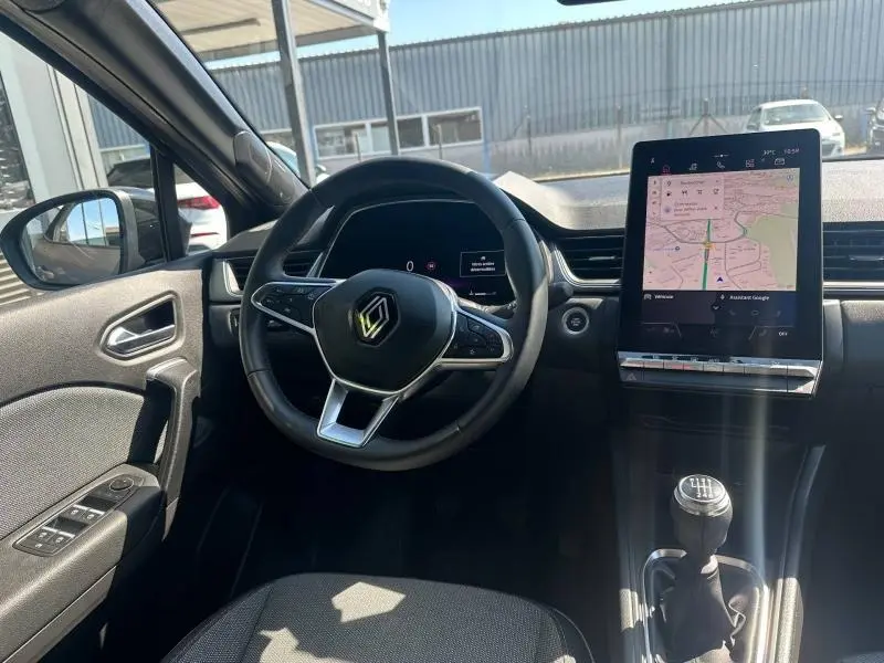 Vue intérieure avant du Renault Captur 2025, volant multifonction et écran tactile GPS, avec levier de boîte manuelle.