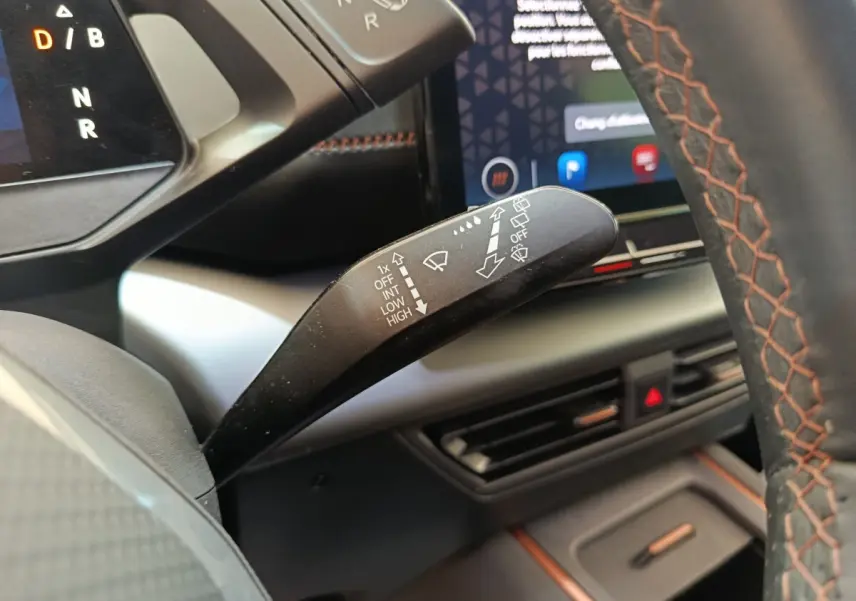Gros plan sur la commande des essuie-glaces dans l’habitacle du CUPRA Born 230ch, volant cuir avec surpiqûres orange visible.