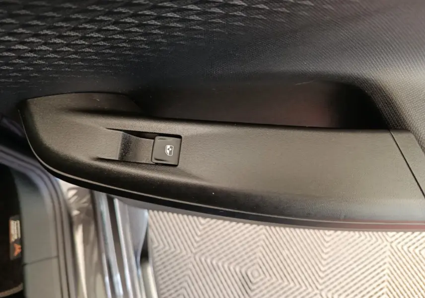 Détail de la commande de lève-vitre électrique sur la porte intérieure côté conducteur d’une CUPRA Born gris foncé.