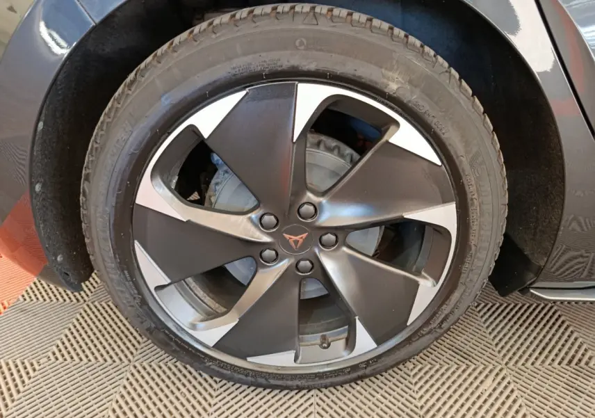 Gros plan sur la roue avant gauche de la CUPRA BORN gris foncé, mettant en valeur la jante bi-ton au design moderne.