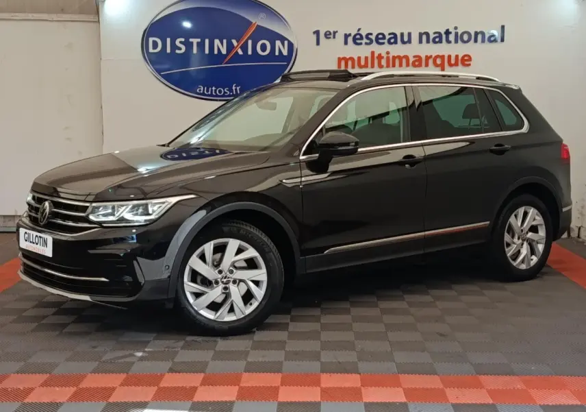 Volkswagen Tiguan noir 2021 en vue profil côté gauche, avec jantes alliage et barres de toit chromées visibles.