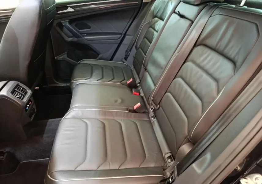Vue intérieure côté droit des sièges arrière en cuir noir du Volkswagen Tiguan 2.0 TDI 150 DSG7 Elegance 2021 avec ventilation et commandes visibles.