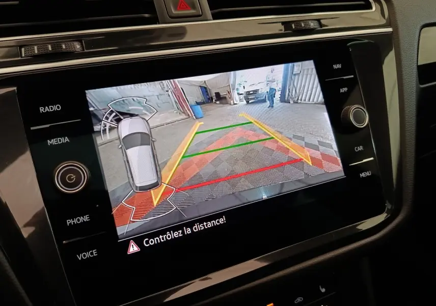 Écran tactile intérieur du Volkswagen Tiguan 2021 montrant l’aide au stationnement avec caméra de recul et guidage coloré.