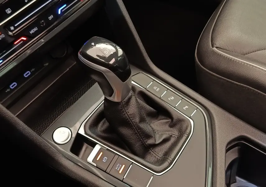Gros plan sur la console centrale noire du Volkswagen Tiguan 2.0 TDI 150 DSG7 avec levier de vitesse automatique et boutons de contrôle.