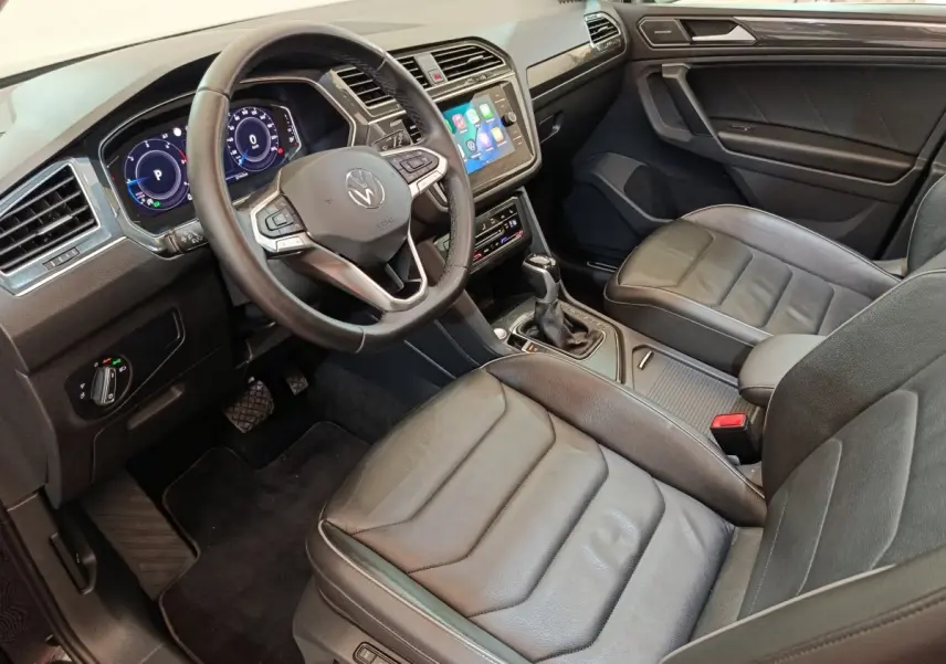 Vue intérieure côté conducteur du Volkswagen Tiguan 2.0 TDI noir, volant cuir multifonctions et écran tactile central.