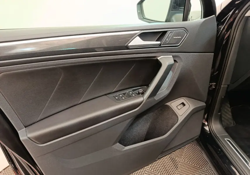 Vue intérieure de la porte avant gauche noire du Volkswagen Tiguan 2.0 TDI 150 DSG7 Elegance avec commandes et insert Harman Kardon.