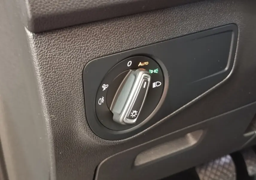 Gros plan sur la commande des phares noire à molette du Volkswagen Tiguan 2.0 TDI 150 DSG7 Elegance, intérieur gris.