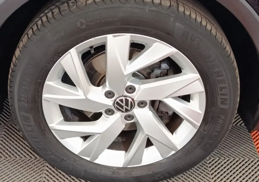 Gros plan sur la jante alliage argentée avec logo Volkswagen d’un Volkswagen Tiguan noir, pneu Michelin visible.