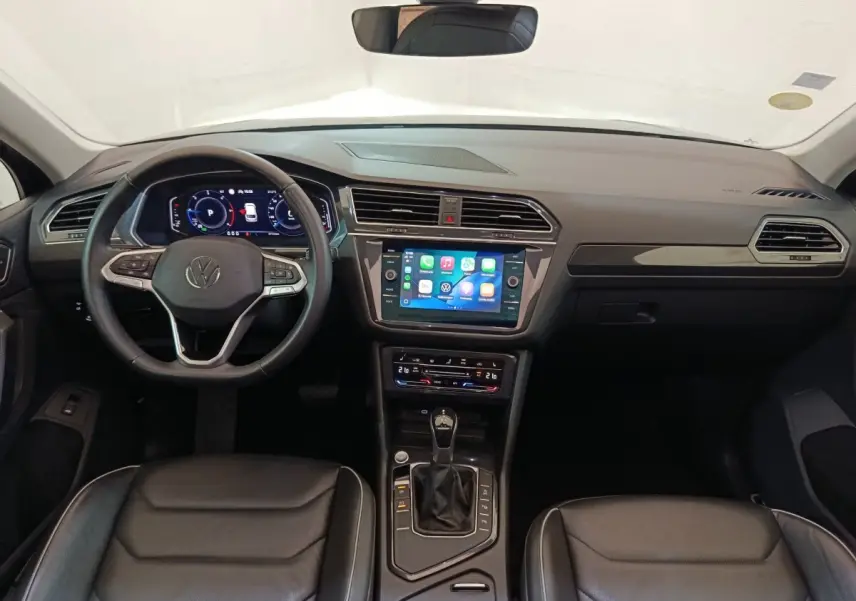 Vue intérieure du tableau de bord du Volkswagen Tiguan 2021, volant cuir multifonctions et écran tactile central allumé.