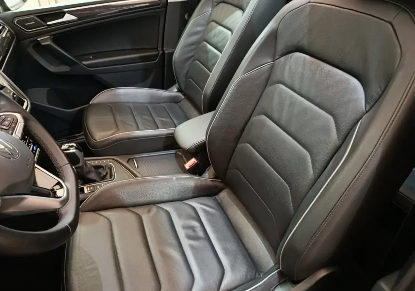 Vue intérieure côté conducteur du Volkswagen Tiguan 2.0 TDI 150 DSG7 Elegance noir avec sièges cuir et volant multifonctions.