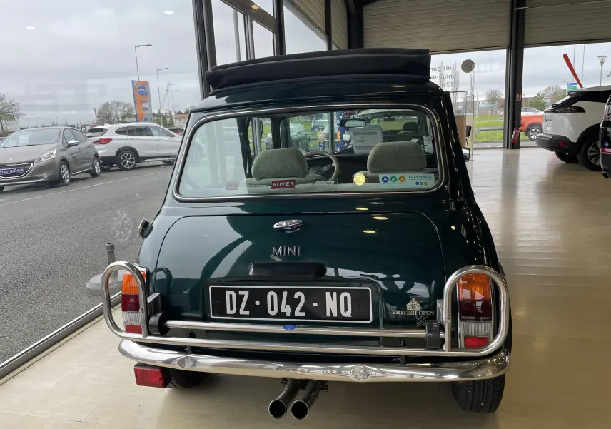 Vue arrière d'une MINI 1.3 i British Open 1995 en British Racing Green avec toit ouvrant et double sortie d'échappement.