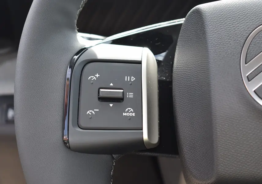 Gros plan sur les commandes à gauche du volant du Citroën C3 2025 bleu toit noir, avec régulateur de vitesse et mode.