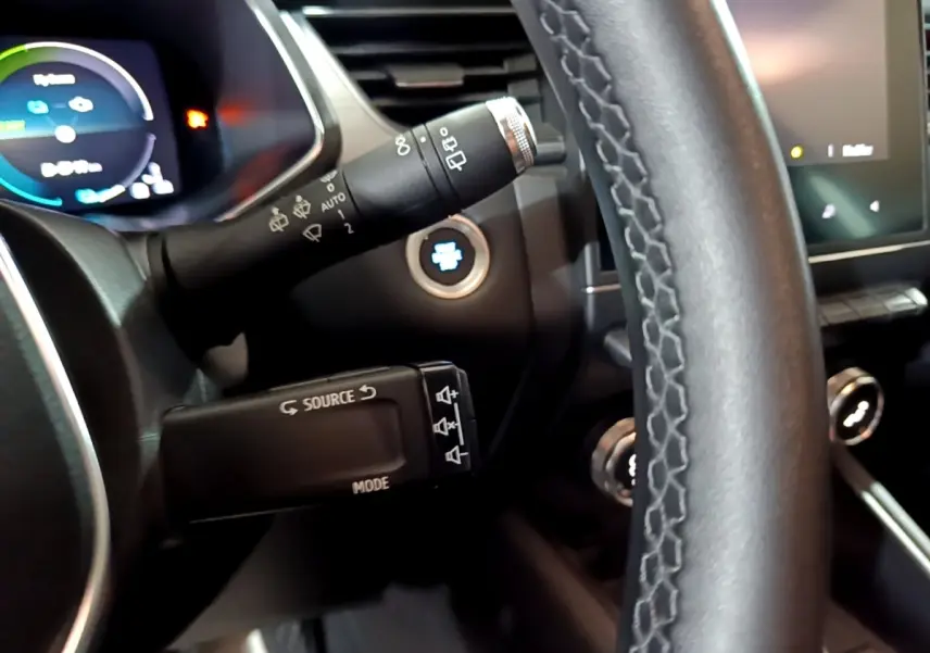 Gros plan intérieur sur le volant cuir et commandes multifonctions du Renault Captur Intens E-Tech hybride gris clair.