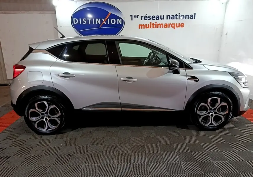 Vue de profil côté gauche d'un Renault Captur gris clair Intens E-Tech hybride rechargeable 2021 dans un showroom.