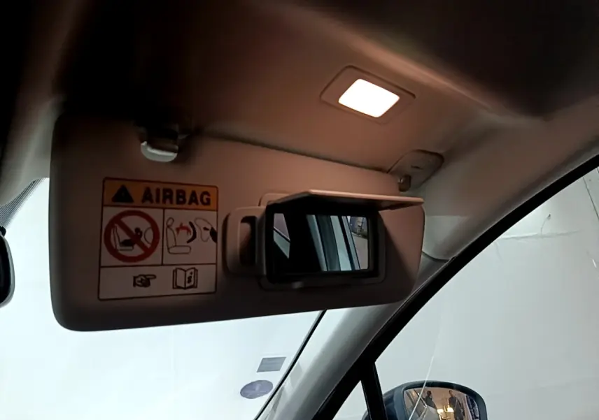 Détail du pare-soleil côté conducteur avec miroir éclairé et avertissement airbag dans un Renault Captur gris clair.