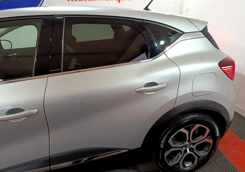 Vue côté droit arrière du Renault Captur gris clair hybride rechargeable avec jantes alliage et feux arrière LED allumés.