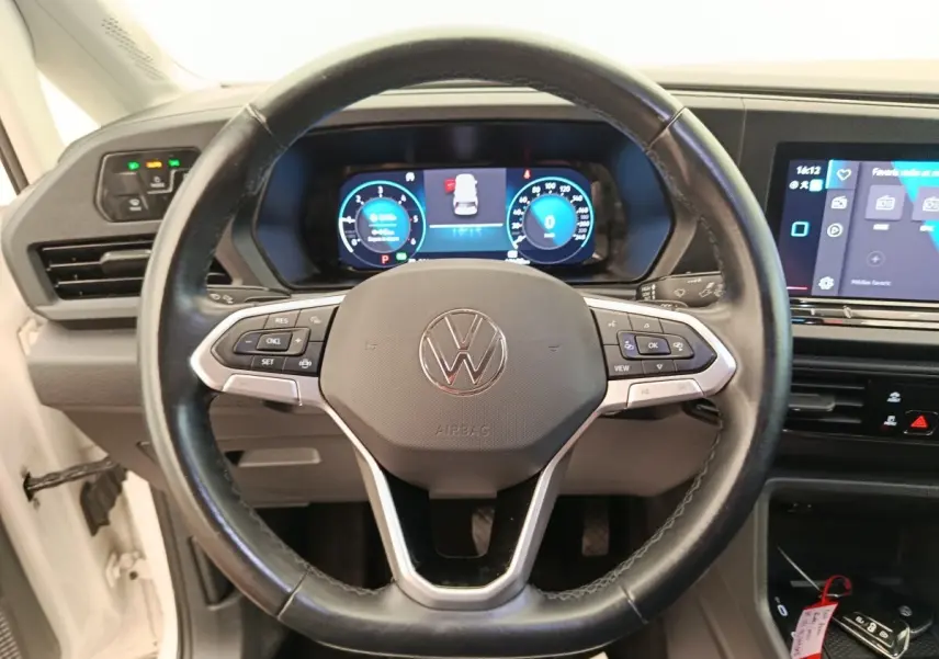 Vue centrée sur le volant cuir noir du Volkswagen Caddy 2022 avec tableau de bord digital et écran tactile.