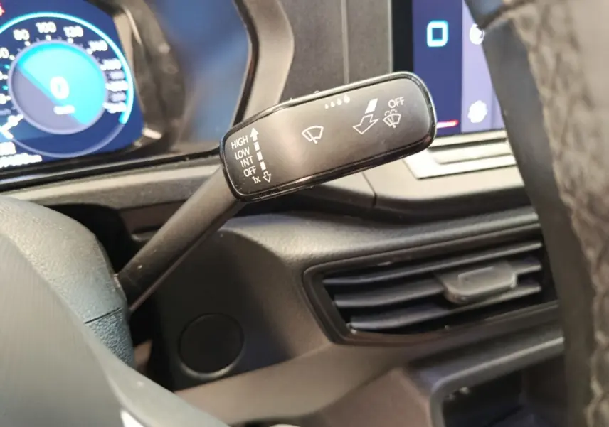 Gros plan sur la commande d’essuie-glace à gauche du volant dans l’habitacle du Volkswagen Caddy blanc 2022.