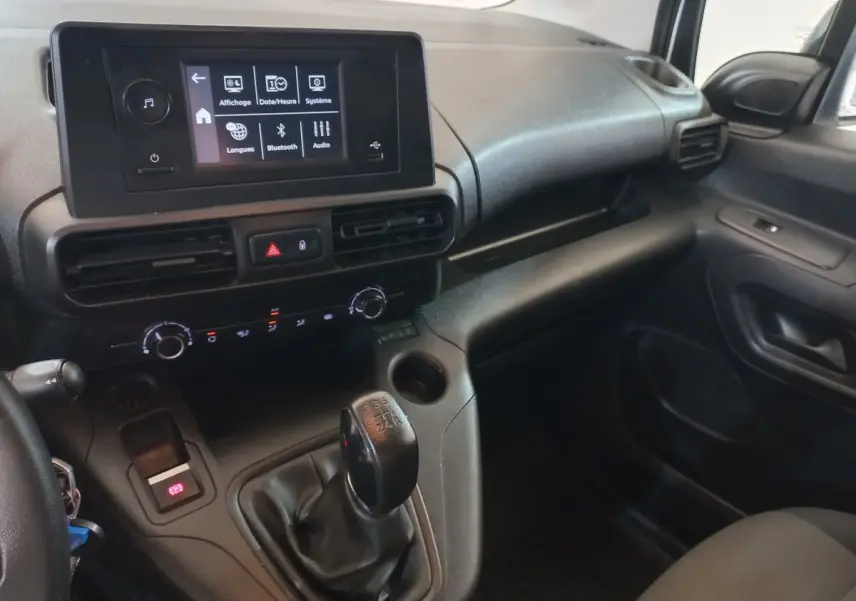 Vue intérieure côté passager du tableau de bord noir du Peugeot Partner 2021 avec écran tactile et levier de vitesses manuel.