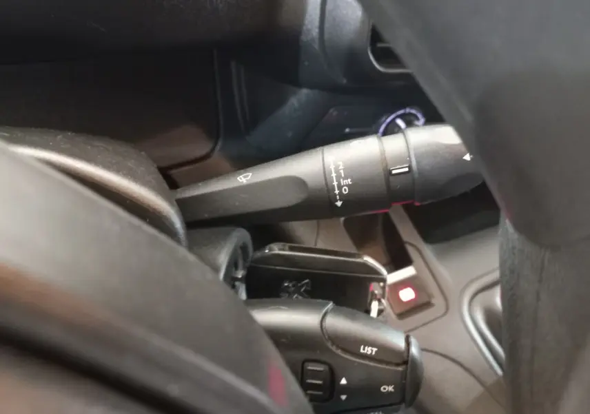 Gros plan sur la commande des essuie-glaces et du régulateur de vitesse dans l'habitacle du Peugeot Partner blanc.