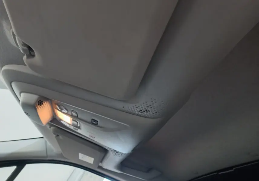 Vue intérieure du plafond avant du Peugeot Partner blanc 2021 avec éclairage de cabine allumé et pare-soleil côté conducteur.