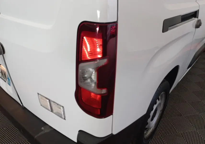 Vue arrière droite d’un utilitaire Peugeot Partner blanc avec feu arrière allumé et porte latérale coulissante.