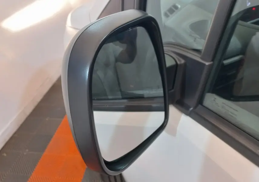 Gros plan sur le rétroviseur côté gauche du Peugeot Partner blanc, avec reflet partiel de l'intérieur du véhicule.