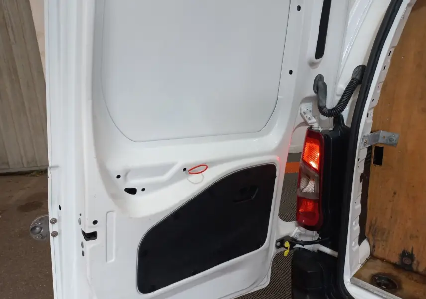 Vue rapprochée de la porte arrière droite blanche du Peugeot Partner 2021, avec feu arrière et intérieur bois visible.