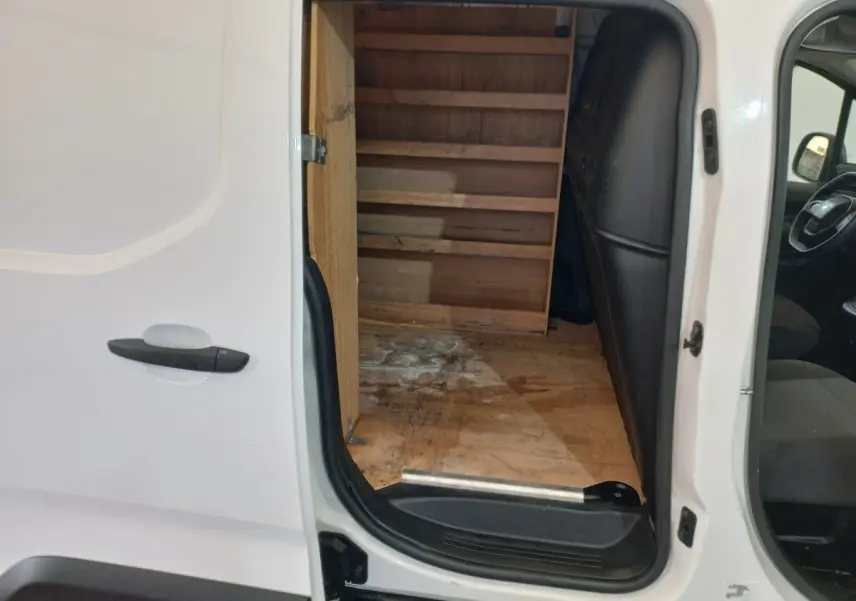 Vue latérale gauche du Peugeot Partner blanc 2021 avec porte coulissante ouverte montrant l’intérieur utilitaire en bois.