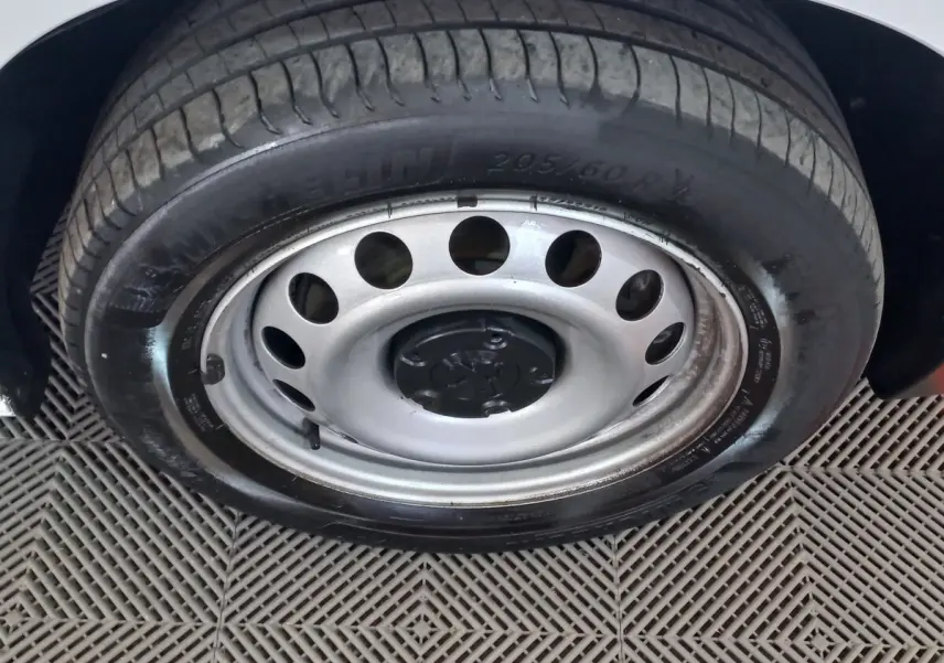 Gros plan sur la roue avant droite avec jante acier et pneu Michelin du Peugeot Partner blanc 2021.
