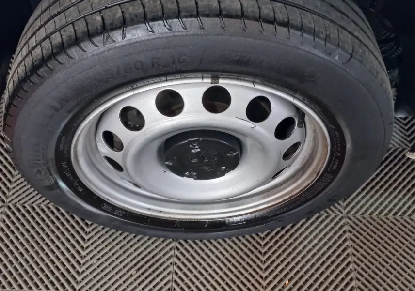 Gros plan sur la roue acier avec pneu du Peugeot Partner blanc, montrant la jante à trous ronds.