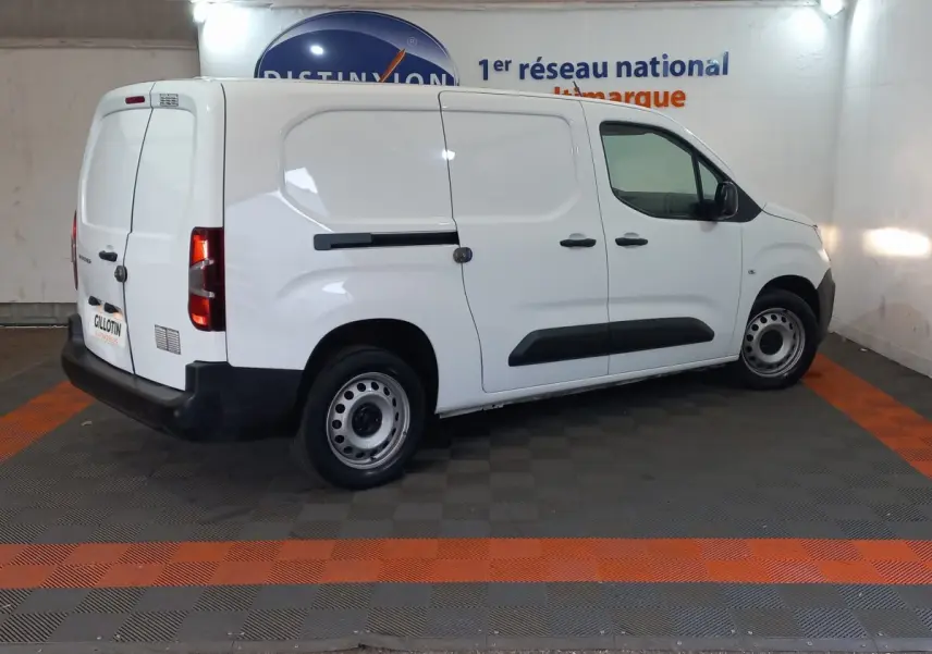 Vue 3/4 arrière droite d’un utilitaire Peugeot Partner blanc avec portes latérales et arrière pleines, en intérieur.
