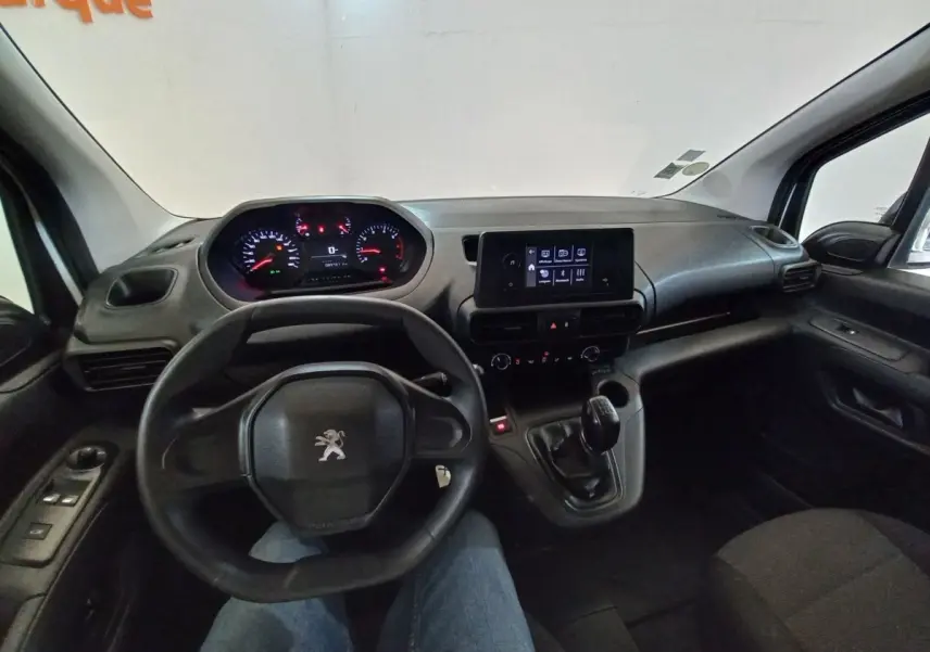 Vue intérieure du poste de conduite du Peugeot Partner blanc, avec volant, tableau de bord numérique et écran central tactile.