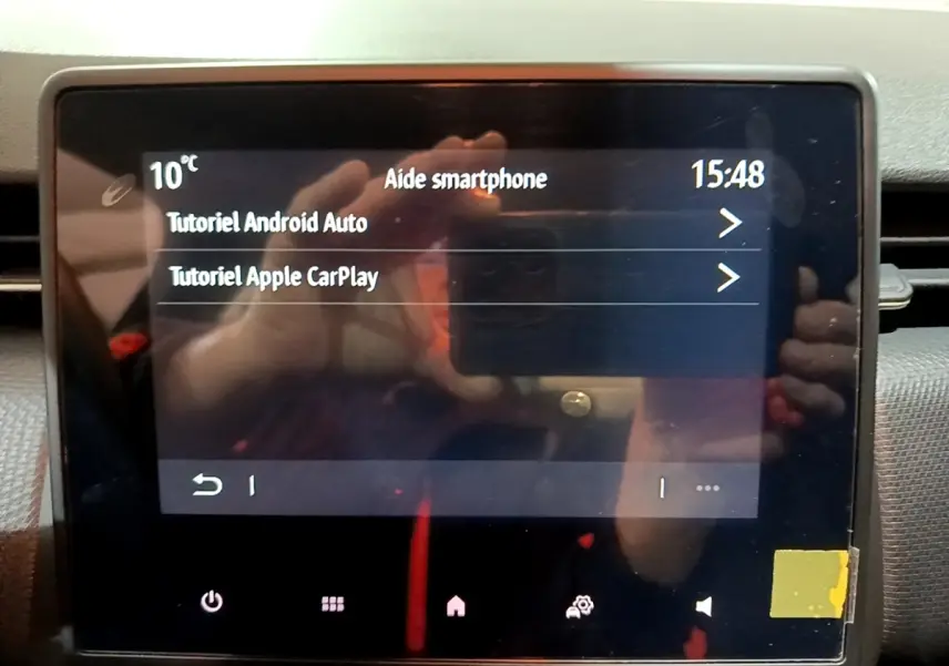 Écran tactile central de la Renault Clio gris clair 2023 affichant les tutoriels Android Auto et Apple CarPlay.