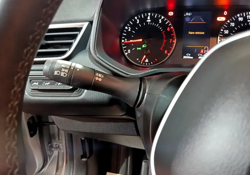 Gros plan sur le combiné d'instruments et le volant cuir noir de la Renault Clio gris clair, affichage digital allumé.