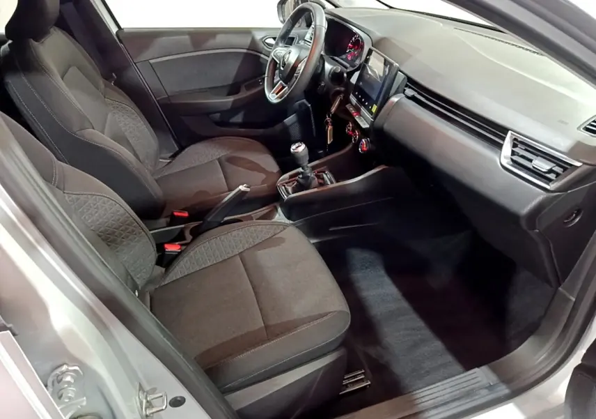 Vue intérieure côté conducteur de la Renault Clio gris clair 2023, avec tableau de bord moderne et boîte manuelle.