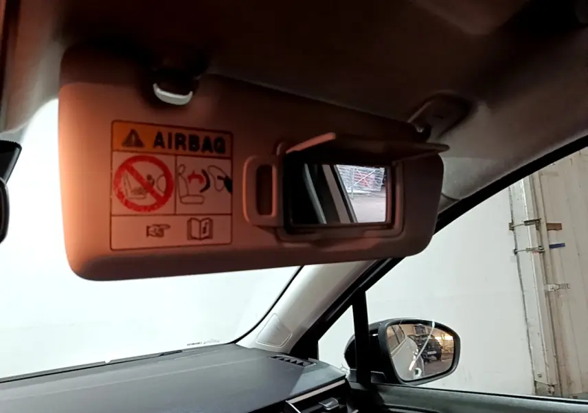 Vue intérieure côté conducteur de la Renault Clio gris clair 2023, avec pare-soleil ouvert et miroir de courtoisie visible.
