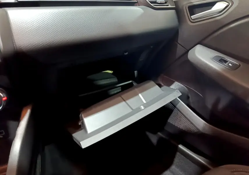 Intérieur Renault Clio 2023 gris clair, vue côté passager sur boîte à gants ouverte et tableau de bord texturé.