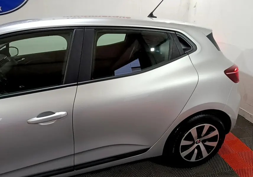 Vue latérale droite d'une Renault Clio 2023 gris clair, mettant en valeur la ligne fluide et les jantes stylisées.