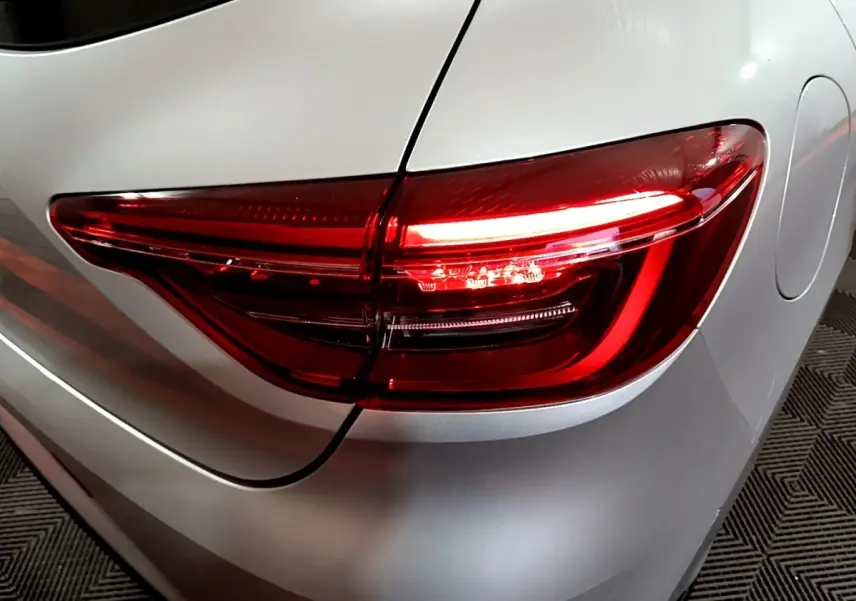 Gros plan sur le feu arrière droit rouge d'une Renault Clio gris clair, vue arrière côté droit.