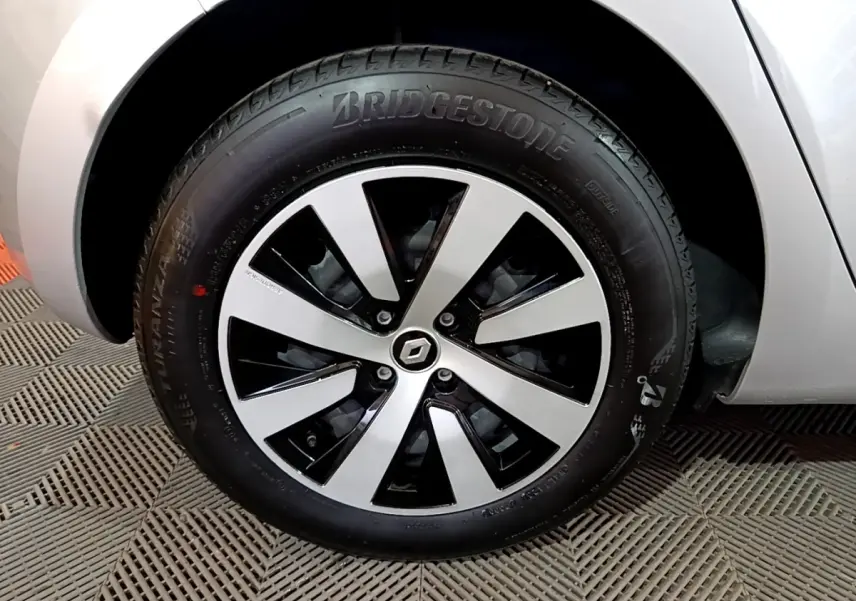 Gros plan sur la roue avant droite d'une Renault Clio gris clair 2023 avec jante alliage bicolore et logo Renault central.