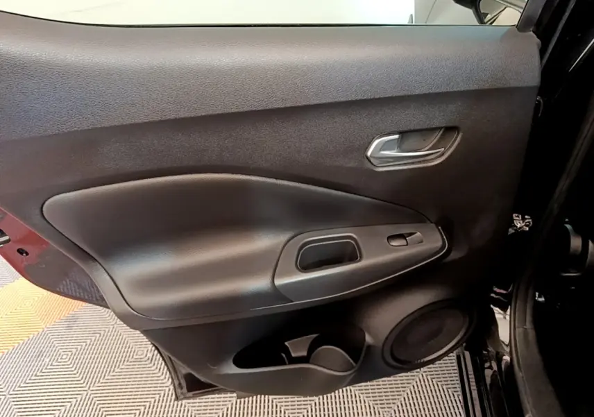 Vue intérieure de la porte arrière gauche noire du Nissan Juke 2022 avec poignée et haut-parleur intégrés.